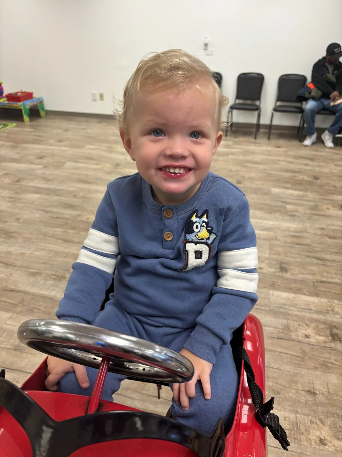 Smiling child in a red salon car chair
