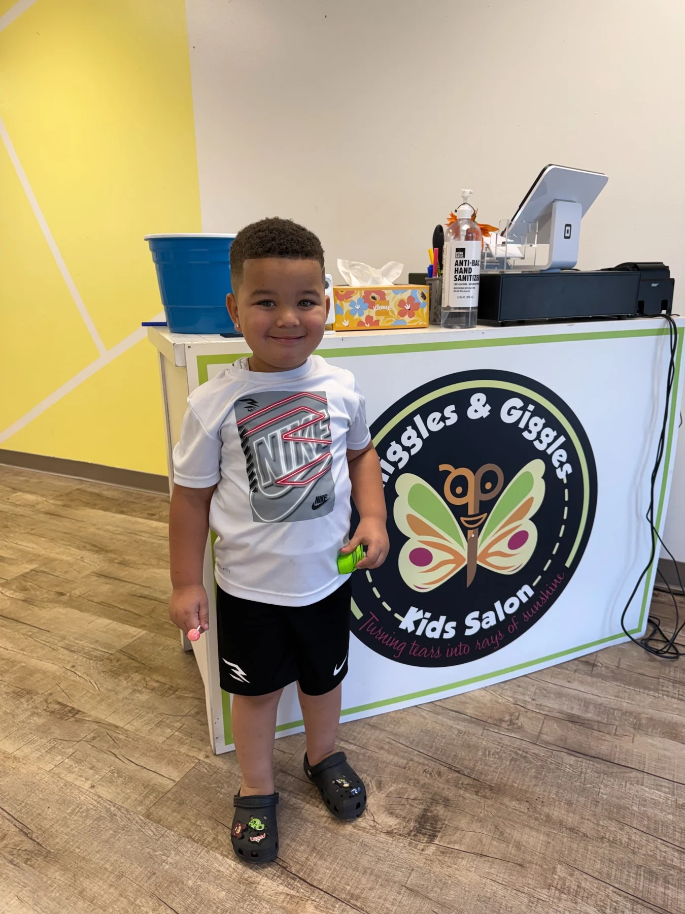 Smiling child beside the Sniggles & Giggles salon counter